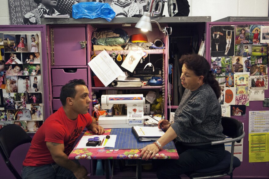 Performer Paulo dos Santos (left), who plays one of the central characters in "Out of this World," speaks with Cloty Gutierrez, the head of costume repair.