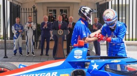IndyCar Series driver David Malukas, right, exits a race car following a demonstration as Felix Rosenqvist, the 2026 Indy 500 winner, from left, Alex Palou, the reigning IndyCar champion, Bud Denker, Freedom 250 Grand Prix chair and Penske Corp. president, President Donald Trump, Roger Penske, chairperson and founder of Penske Corp., and Fox Sports CEO Eric Shanks watch on West Executive Drive at the White House during a showcase for the upcoming Freedom 250 Grand Prix auto race, Monday, July 13, 2026, in Washington.