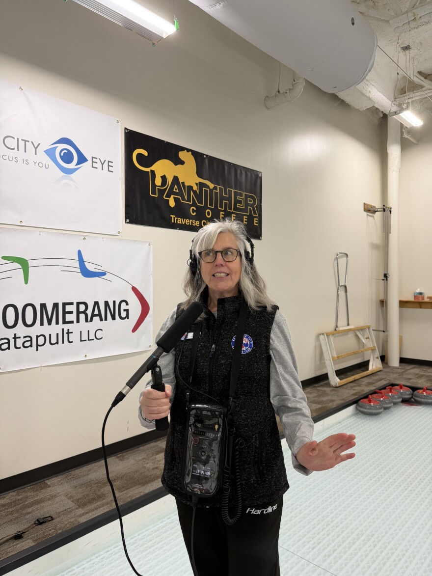 Cara Colburn gives radio a try while IPR's Austin Rowlader tries out curling. (Vivian La, IPR News)