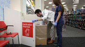 CVS Pharmacist Raphael Lynne (left), D., MBA, and Stephanie Garcia, a Pharmacy tech., check the medication disposal box where people can drop off their expired, unused or unwanted medications for safe disposal.