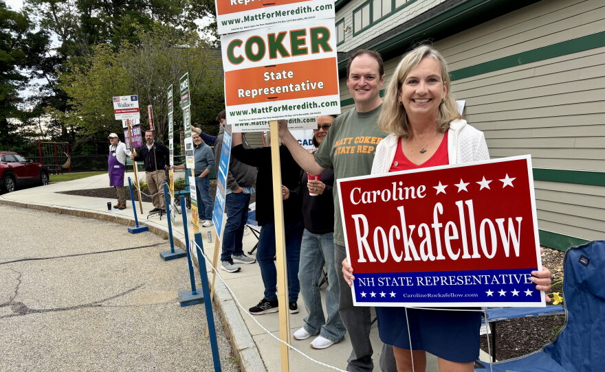 A candidate for the State House holds up a sign at the polls in Meredith. 