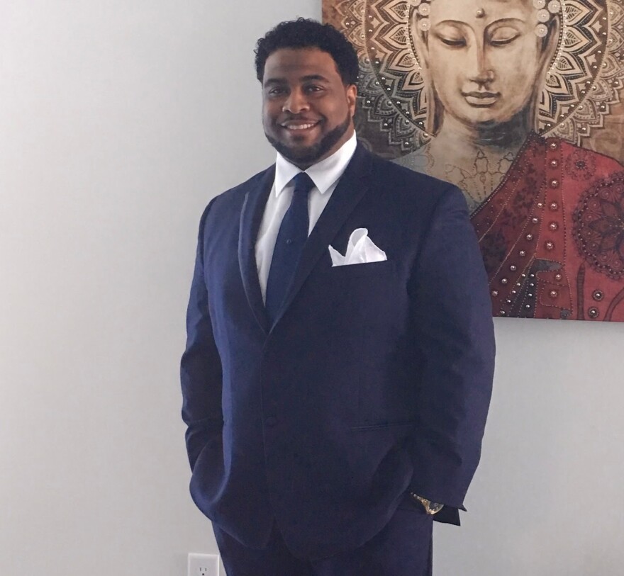 James Austin poses for a photo in a blue suit with a blue tie. 