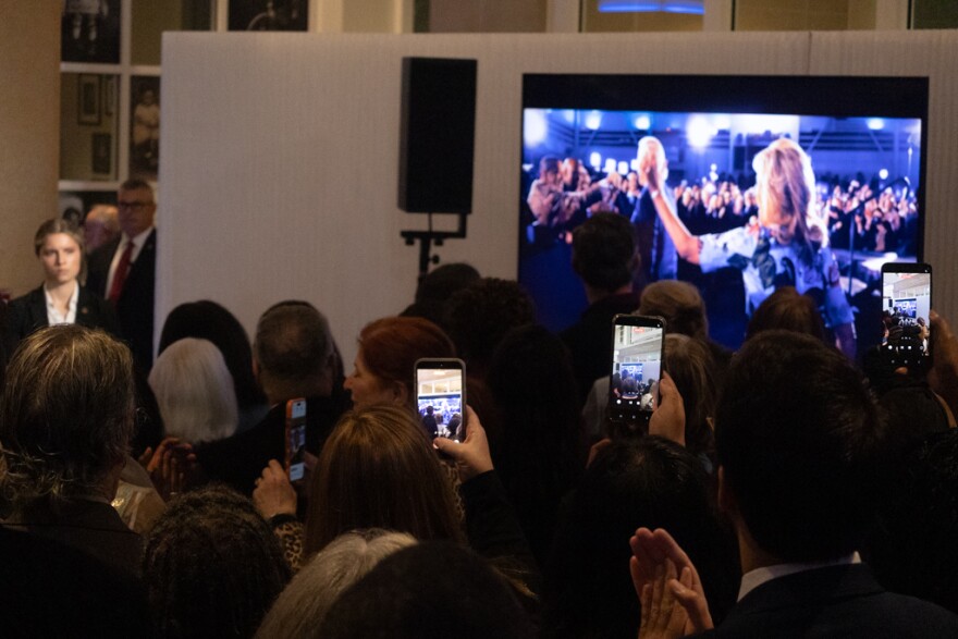 An audience at the Columbia Museum of Art watches a video that retells Joe Biden's road to the Oval Office.
