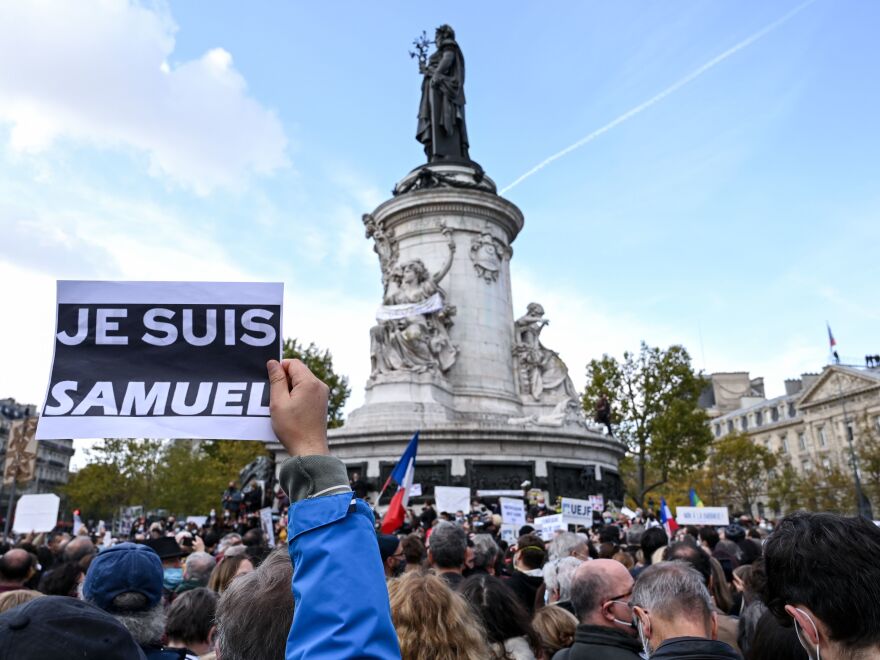 A demonstrator carries an "I am Samuel" sign as people gather Sunday in Place de la République in Paris to pay tribute to slain history teacher Samuel Paty. Similar rallies took place in other French cities as the country reels from the attack.