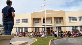 Tracie Griffith looks on at the students, faculty and community gathered at the front of Waldo Community School. Griffith is treasurer of the school's PTO and has been an active spokesperson vying to keep the school where her family has gone for three generations open. Conor Soper/WUFT News