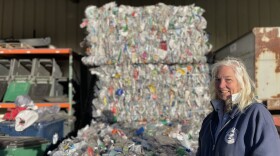 Denise Cumings, crew chief, stands in front of a bale of recycling at the Hooksett Transfer Station. (Mara Hoplamazian/NHPR)