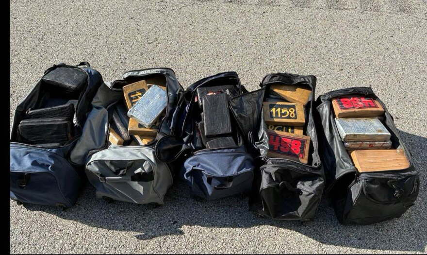 Multiple duffel bags of cocaine laid out on the road.