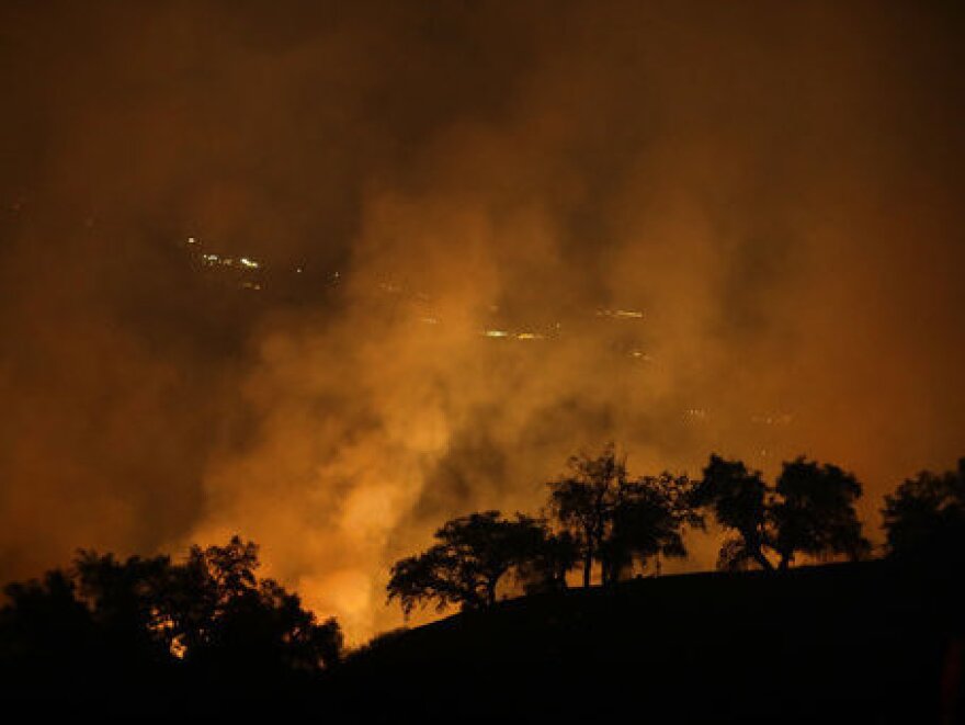 The orange glow of one of California's many wildfires can be seen Friday from a hilltop in Geyserville, Calif.