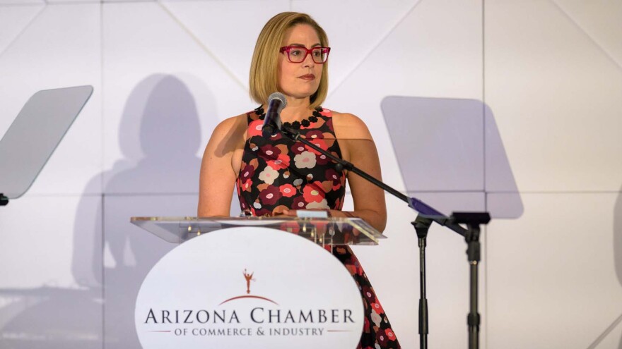 Woman in floral dress speaks at podium