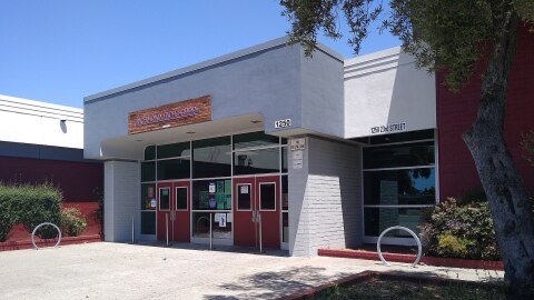 A white building with red doors and a few red walls. A sign on the building reads: Richmond High School. 