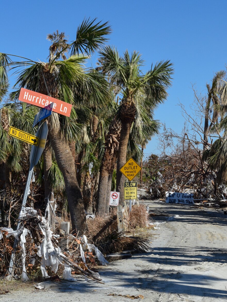 An "If you shoot, we will loot" sign sits along Hurricane Lane on Sanibel, Wednesday, Oct. 8, 2022. Police officers patrol the streets during the islands 7 p.m. to 7 a.m. curfew. 