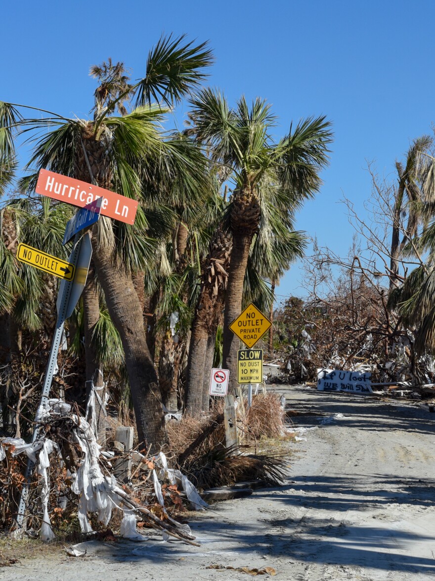  An "If you shoot, we will loot" sign sits along Hurricane Lane on Sanibel, Wednesday, Oct. 8, 2022. Police officers patrol the streets during the islands 7 p.m. to 7 a.m. curfew. &#13;
