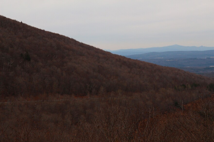 A reddish brown mountain with blue mountains in the background.