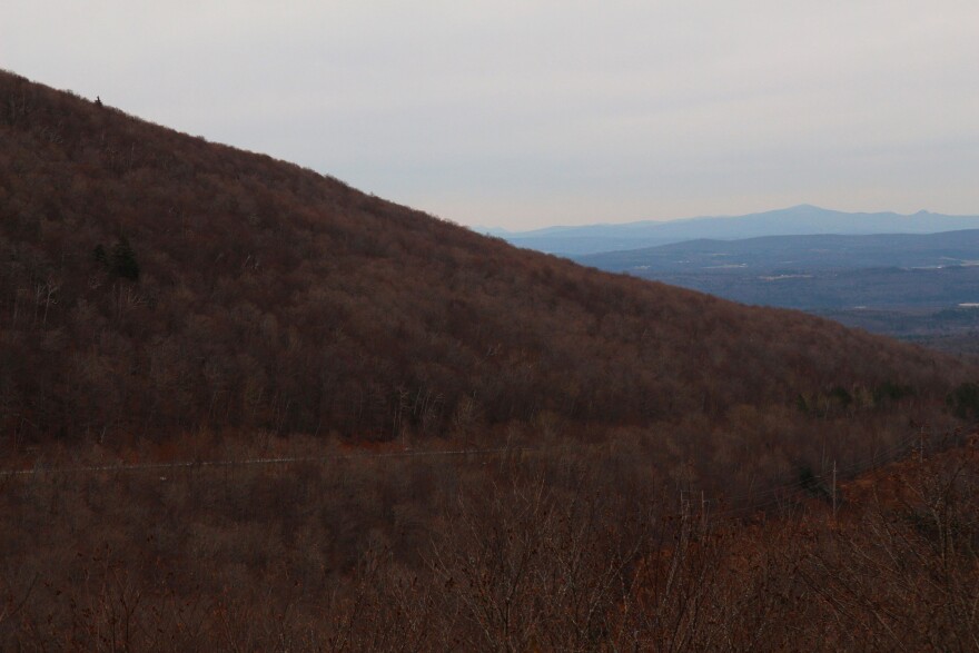 A reddish brown mountain with blue mountains in the background. 