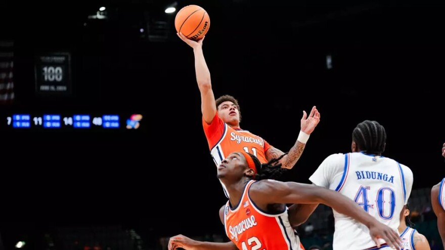 Guard Naithan George (11, Orange) goes up for a lob over Kansas big man Flory Bidunga (40, White)