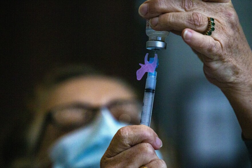 Registered Nurse Delia Murphy dispenses a dose of the Moderna COVID-19 vaccine into a syringe at the Gillette Stadium vaccination site. (Jesse Costa/WBUR)