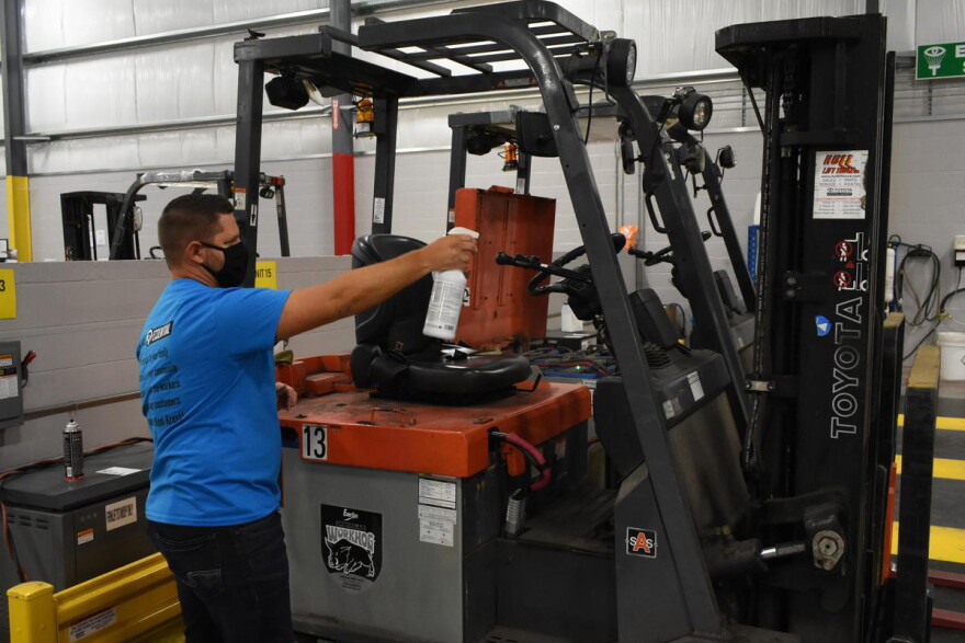 A worker sprays down a forklift in an Elkhart factory in accordance with the company's COVID-19 safety standards.
