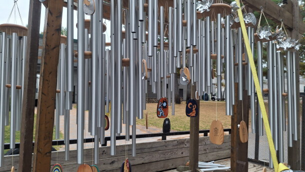 Dozens of wind chimes hang from wooden beams strapped to the bed of a truck.