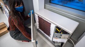 Alana Vilagi, a reseach engineer at the Alaska Center for Energy and Power, with an electric thermal storage heater with the cover off exposing the bricks. 