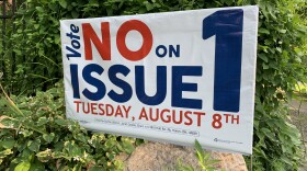 A no on Issue 1 yard sign over a large rock