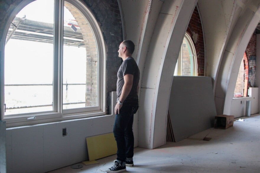 Christopher Cordero of EB Realty Management Corp. looks out the windows of the Divine Lorraine Hotel. (Dean Russell/Here & Now)