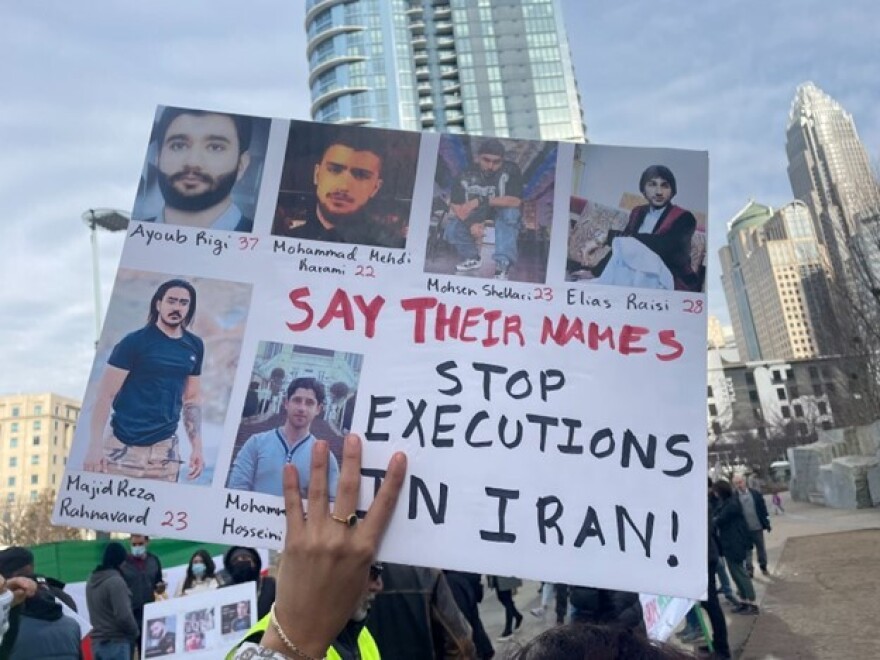 A protester holds up a posterboard with the names and faces of some of the people who have been executed by the Islamic Republic since the start of unrest.