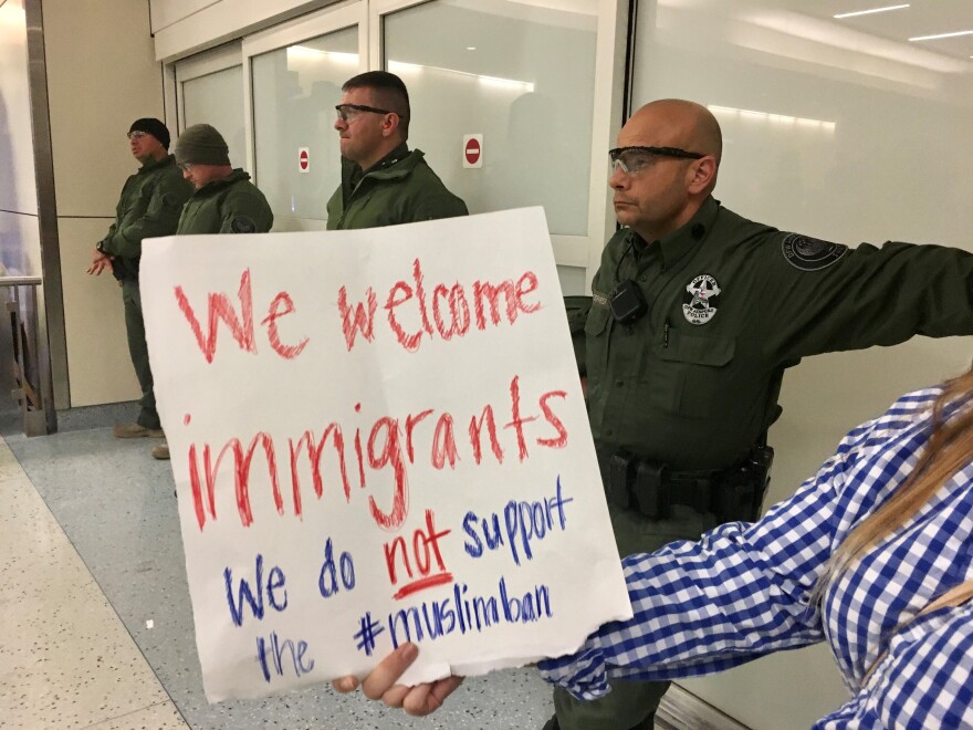 A woman holding a protest sign was one of hundreds of people who showed up at Dallas-Fort Worth International Airport on January 28, 2017, shortly after former President Donald Trump's travel ban took effect. Many protestors stayed there past midnight. 