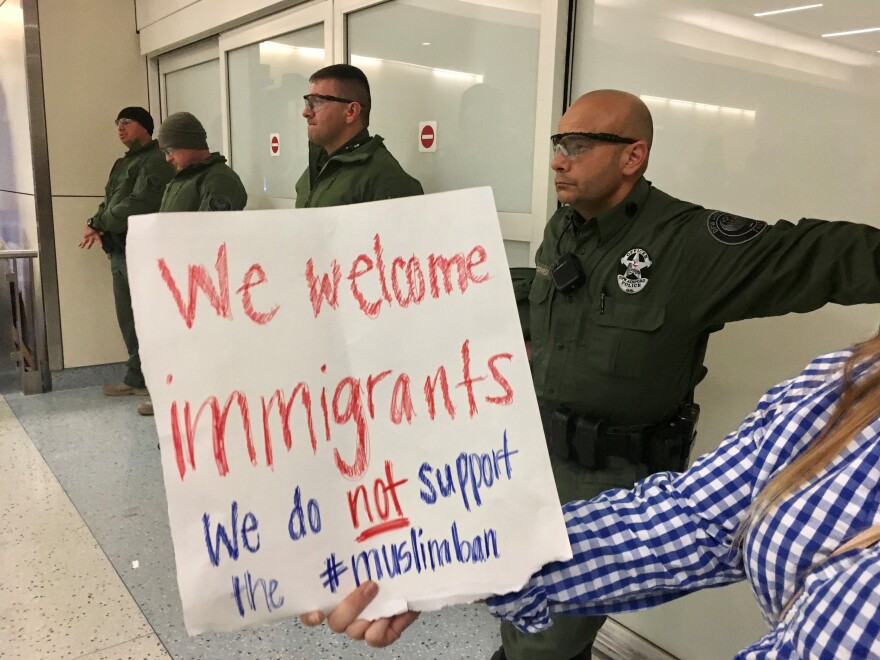 A woman holding a protest sign was one of hundreds of people who showed up at Dallas-Fort Worth International Airport on January 28, 2017, shortly after former President Donald Trump's travel ban took effect. Many protestors stayed there past midnight. 