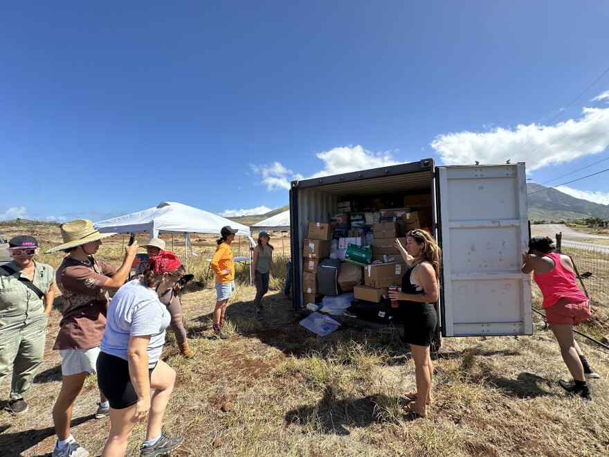 Gretchen Losano, center in black, motions to the overflowing container as it's opened. Volunteers sorted about one third of its contents in several hours.