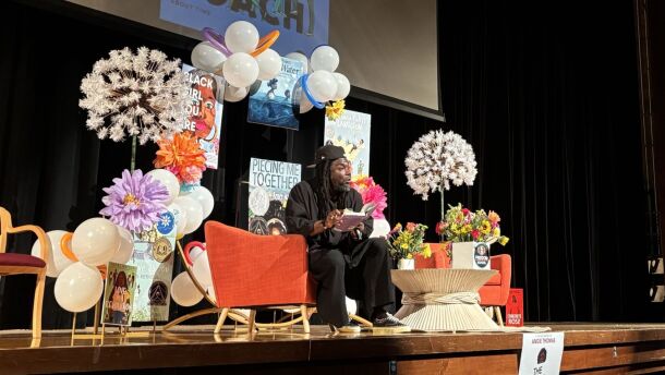 Writer on a stage expressively reads to an auditorium.