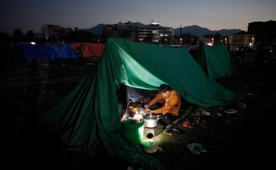 A Nepalese man cooks food inside a tent as people relocate to open ground from fears of earthquake tremors in Kathmandu, Nepal, on Monday evening.