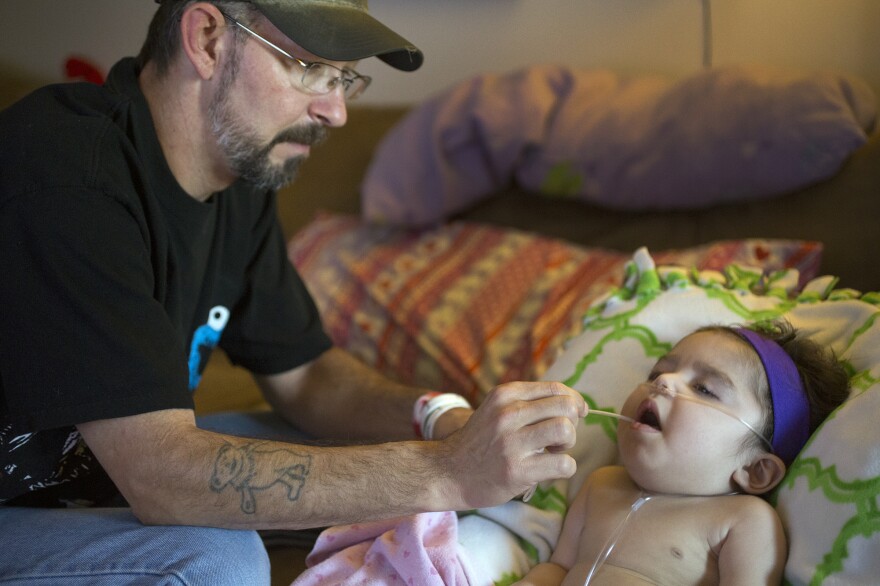 Anthony Shaffer uses a suction device to clear the mouth of Jaylah Donaire-Bechtel, in Harrisburg, Pa. Jaylah has Krabbe disease and can't swallow or speak.