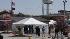 Workers wait in line to enter the Tyson Foods pork processing plant in Logansport, Ind., Thursday, May 7, 2020. The plant was expected to Thursday after closing on April 25 after nearly 900 employees tested positive for the coronavirus. Workers won't be able to return to work until they get tested.