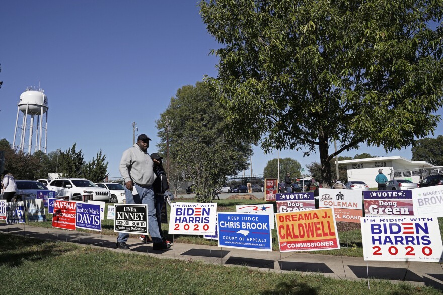 Voters walk past campaign signs at the Graham Civic Center polling location in Graham, N.C., Tuesday, Nov. 3, 2020.