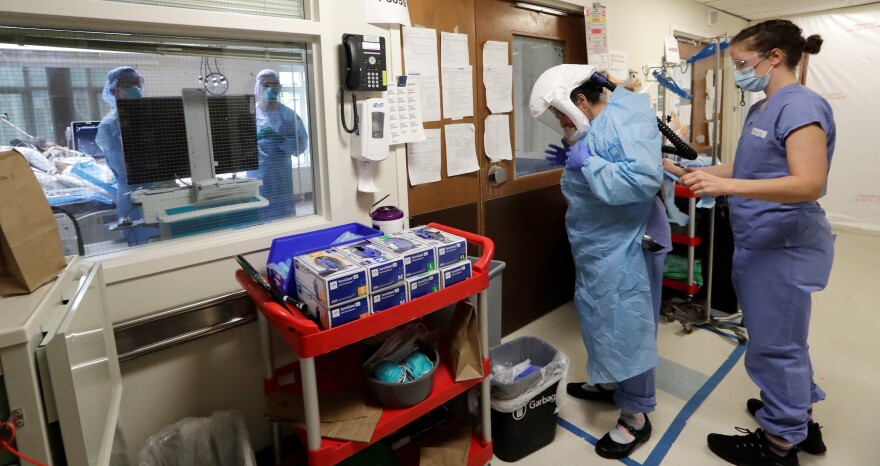 A medical worker is assisted into personal protective equipment on May 8 before stepping into a patient's room in the COVID-19 intensive care unit at Harborview Medical Center in Seattle.