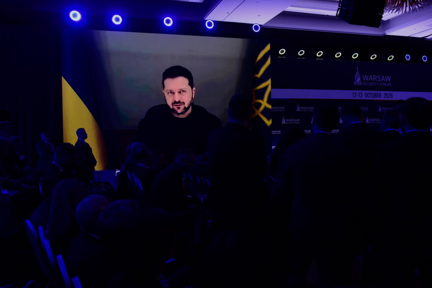 People watch Ukrainian President Volodymyr Zelenskyy on a large screen as he speaks at the Warsaw Security Forum in Warsaw, Poland, Monday, Oct. 12, 2026. (AP Photo/Attila Husejnow)
