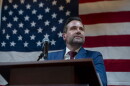 Josh Turek appears at a podium, in front of an American flag.
