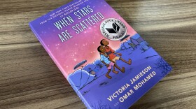 A book cover with purple and pink colors on a wooden desk