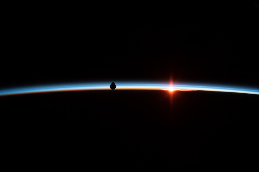 The uncrewed SpaceX Crew Dragon spacecraft is silhouetted against the Earth's horizon during Demo-1, the first flight of NASA's Commercial Crew Program to the International Space Station. The vehicle ultimately docked to the station's Harmony module after completing several successful demonstrations during approach.