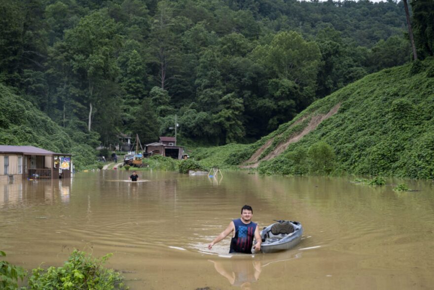 Lewis Ritchie pulls a kayak through floodwater after delivering groceries to his father-in-law on July 28, 2022 outside Jackson in Breathitt County.