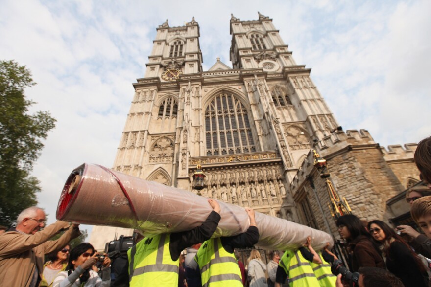 Workers carry in sections of the red carpet at Westminster Abbey, where Prince William and Kate Middleton are scheduled to get married Friday.