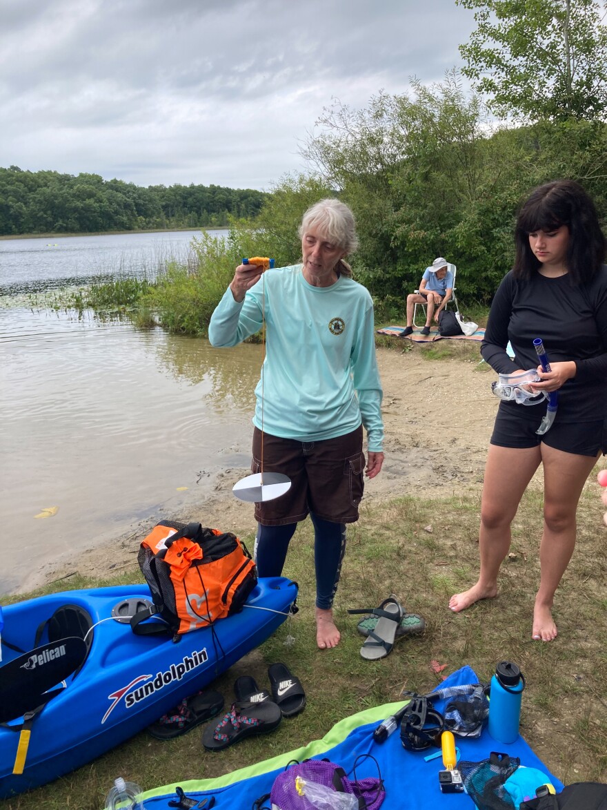 Cara Shillington, a biology professor at Eastern Michigan University, demonstrates how to use a Secchi disk. The device is used to measure water clarity. (Photo: Ellie Katz / Points North)