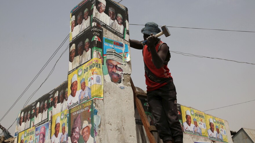A man hammers a wall with elections posters at an open market in Kano, Nigeria, on Friday. The country is preparing for presidential elections on Saturday. President Goodluck Jonathan faces former military ruler Muhammadu Buhari and 13 other candidates in what is seen as the closest presidential race since the end of military rule in 1999.