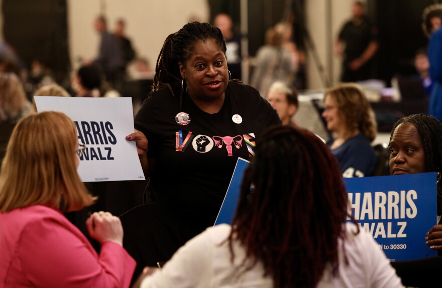 Rakia Hardaway of Rochester brings over Harris signs to friends attending the Monroe County Democrats' gathering at the Hyatt hotel in downtown Rochester.