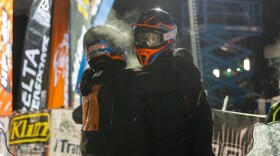 Tyler Aklestad and Nick Olstad embrace moments after crossing the finish line of the 2025 Iron Dog snowmachine race.