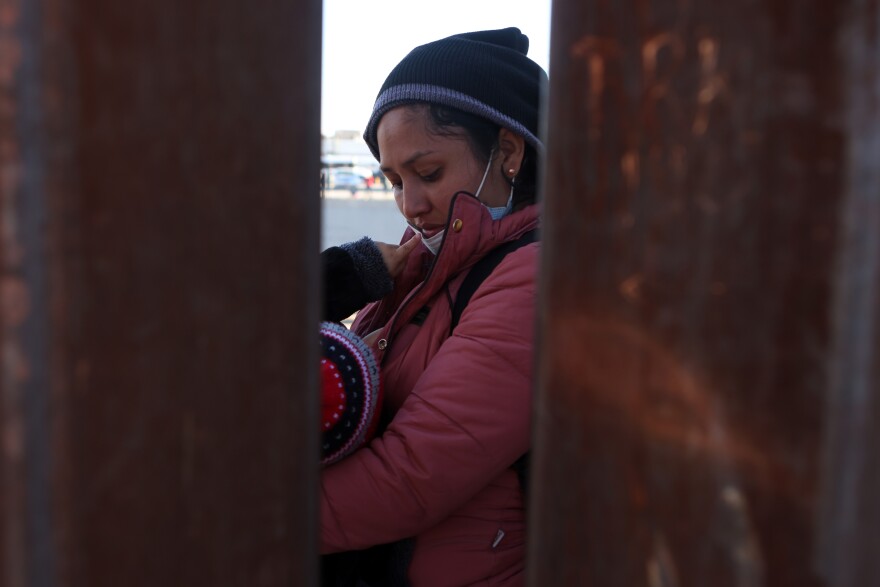 An asylum-seeking migrant from Colombia nurses her child as she waits at the border wall to be processed by U.S. Customs and Border Protection after crossing the Rio Grande River into the United States in El Paso, Texas, U.S., December 21, 2022.