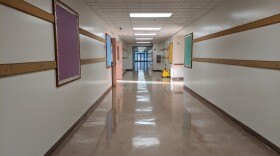 An empty hallway with a display board with a purple backgrond on the left wall