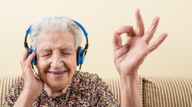 Elderly woman listening and enjoying music while wearing headphones.