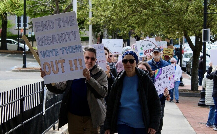 Two protestors marching towards Innes Park. One protestor (left) is holding a sign stating "End the insanity vote them out!!"