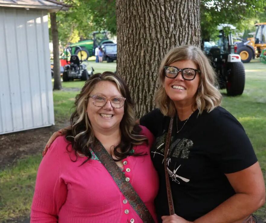 Nana Kasowski, left, poses next to Tara Hanson in front of a tree at the Clay County Fair | MPR News